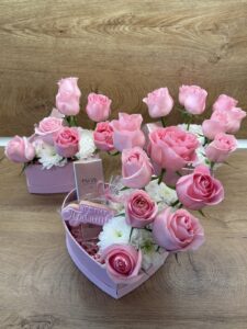 Нежна подаръчна кутия във формата на сърце с розови рози, бели хризантеми, парфюм и празничен медальон „Честит празник“.