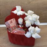 Романтична подаръчна кутия във формата на сърце с бели рози, шоколад Gucci Flora и празничен медальон „Честит празник“.