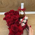 Романтична подаръчна кутия с червени рози, бутилка вино и шоколадови бонбони Ferrero Rocher, поднесени в елегантна аранжировка.