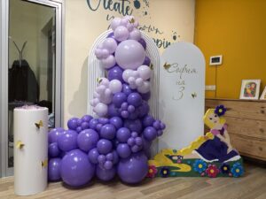 Тематична декорация за детски рожден ден с балони в лилави нюанси, фигура на Рапунцел и персонализиран фон за третия рожден ден на София.