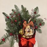 Коледна подаръчна кутия с плюшено мече, шоколадови бонбони, червена панделка и богата декорация от елхови клонки и червени акценти.